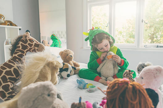 Young Girl (5 yrs old) in Dragon costume having tea party with toys