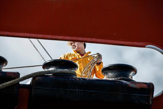 Worker fastening ropes to mooring posts on board oil tanker