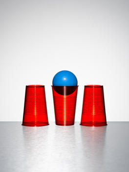 Blue ball in middle of three red cups