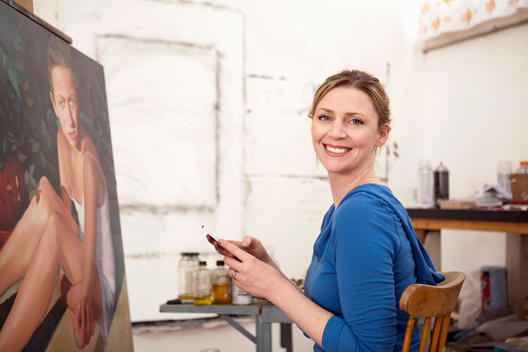 Mid adult woman and oil painting in artist\'s studio, portrait