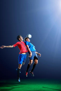 Male soccer players heading ball