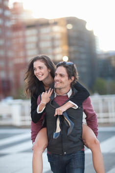 Mid adult man giving girlfriend piggyback in street