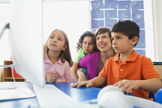 Teacher and children using computer in elementary class