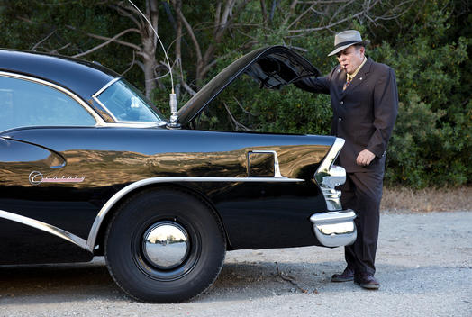 Gary Goltz smokes a cigar as he opens the trunk of his replica cop car from the show Highway Patrol