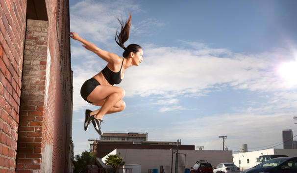 Athletic woman jumping into air, side view