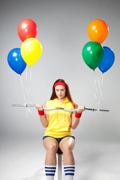 Woman holding barbell with balloons instead of weights