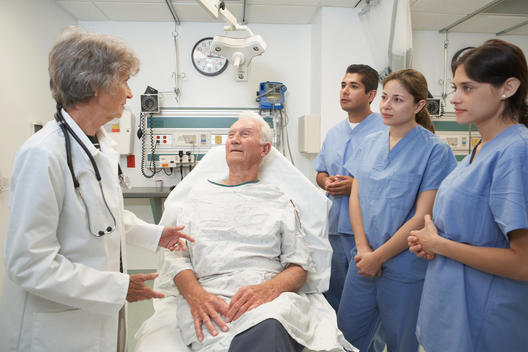 Senior female doctor talking to patient while med students listen