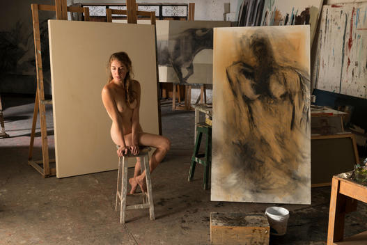 Nude woman modeling for artist in studio