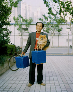 Man With Dog And Two Covered Birdcages, Shanghai Skyline In Background