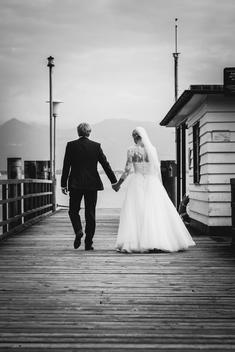 wedding couple walking at the promenade of the lake of Constance, holding hands, bride with veil