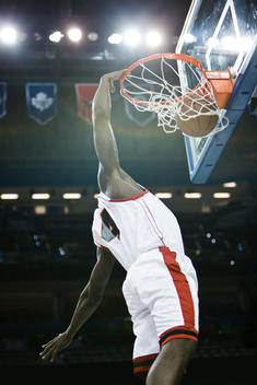 Basketball player slam dunking basketball