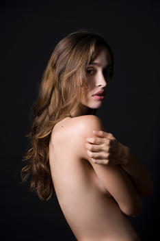 Studio portrait of sultry young woman with arms folded