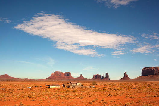 A group of small dwellings sit alone in the desert, surrounded by large rock formations.