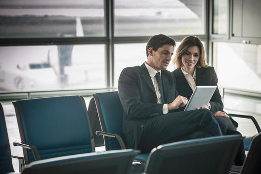 Businesspeople using digital tablet in airport departure lounge