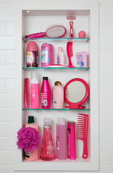 Four bathroom shelves are filled with all pink beauty and hygiene products