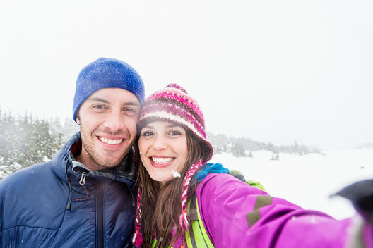 Young couple taking a selfie while on their snowshoeing adventure