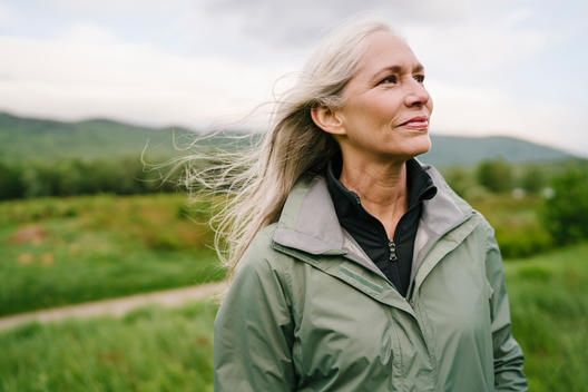 Portrait of a fit healthy older woman with grey silver hair standing near a lake.