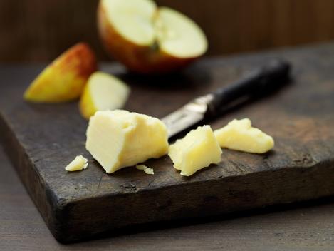 Mature cheddar cheese with apple slices on wood
