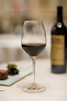 Wine Glass With Red Wine And Bottle On Dinner Table
