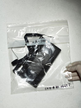 Crime scene evidence- a old vhs tape in an evidence bag with a hand in a rubber glove holding it