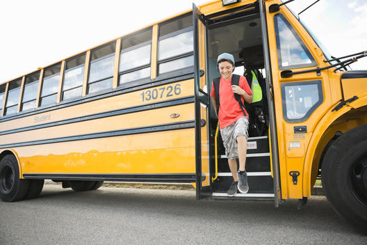 Schoolboy disembarking school bus during field trip
