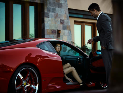 Man holding the door for woman in luxury car.