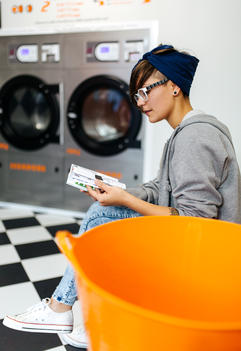 Young woman reading comic strip in a launderette