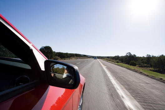 Motion Blur Image Of Red Car Driving On Straight Road