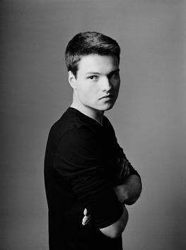 Classic black and white studio portrait of Denys, a teenage Russian guy in simple black shirt. NYC