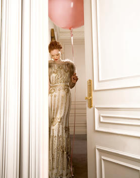 Woman looking down while holding pink balloon through doorway.