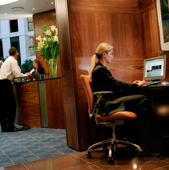 A man in a suit checks into the hotel at Gatwick Airport while a business women works on the computer in the foreground.