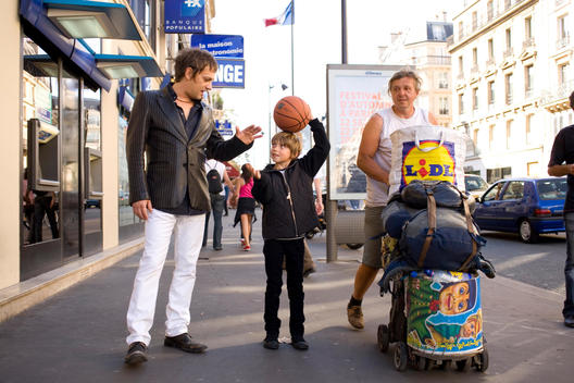 A father and son play with a basketball in the street.