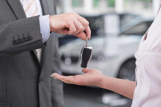 At the car dealer, Salesman handing over car key to client