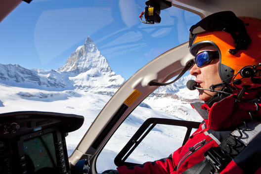 A pilot in a rescue helicopter with the Matterhorn seen from his window. Air Zermatt in the Swiss Alps is one of the busiest and most professional helicopter mountain rescue services in the world.