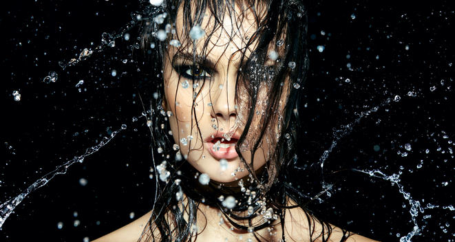 close up of a models face with wet hair all over in front of her face wearing black eyeshadow and smokey eyes