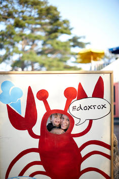 A photo of a little boy and his mother looking through a stand in cutout of a lobster