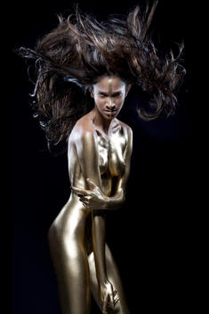 Exotic girl with gold body painting makeup naked and hair style