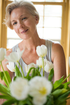 Portrait of a mature blond woman sitting with a vase of tulips