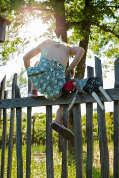girl and doll climbing over fence