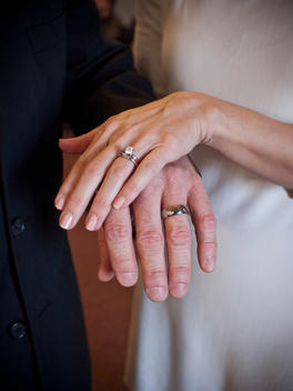 Hands of a newly married husband and wife overlapping show off their wedding rings.
