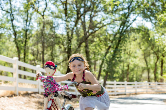 girl and doll wearing masks riding bike