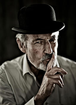 Old man in bowler hat asking you to keep quiet