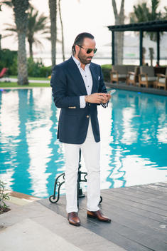 Man in suit on his phone by the pool
