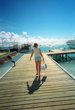 Meerufenfushi (Meeru) Island Resort in the Maldives, A blonde women wearing a crop top and shorts walks to a boat along the pier.