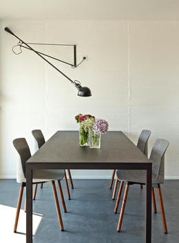 Escorial Apartment, Barcelona, Spain. Close view of modern dining table and chairs with vase filled with flowers. Lamphead hanging over table.