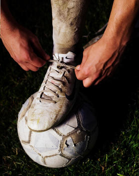 Man tying shoelace on soccer ball