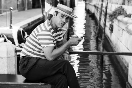 A gondolier takes a rest with his mobile phone.