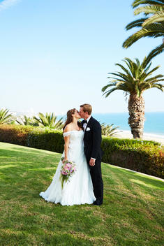 A wedding couple outside with the ocean in the distance