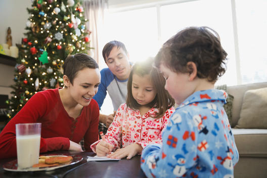Family watching girl write letter to Santa Claus