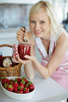 Woman eating jelly from jar in kitchen